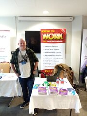 Gerry standing next to a table covered in copies of Working for Work